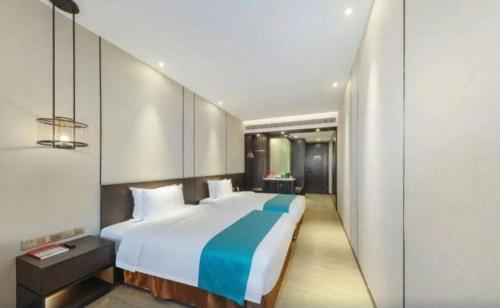 a bedroom with a large bed with a blue blanket at H Life Hotel Nanshan Branch in Shenzhen