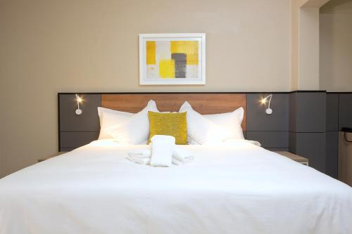 a bedroom with a large white bed with yellow pillows at The Park Lodge Hotel in Pretoria