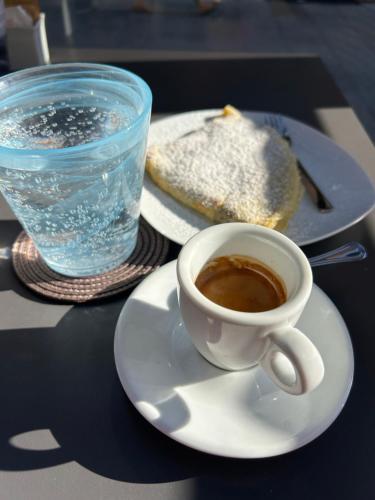 a cup of coffee on a plate next to a glass of water at Blue Roof in Fidenza