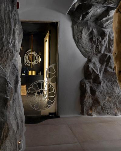 a room with a stone wall and a doorway at Kove Mykonos - A Myconian Collection Hotel in Ornos