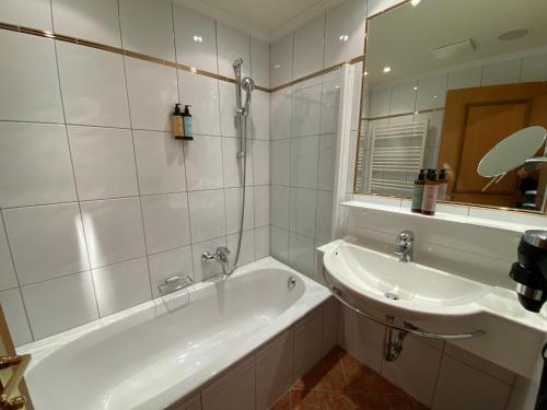 a white bathroom with a tub and a sink at Hotel Steiner Superior in Obertauern