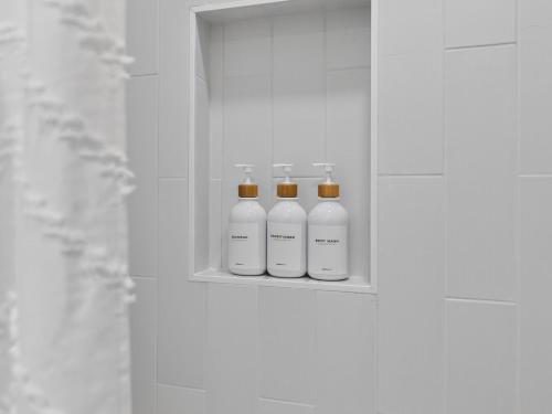 three white bottles sitting on a shelf in a bathroom at 4BR 3Bath Game Room Harvard MIT Apt in Cambridge