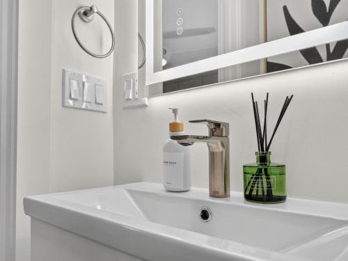 a bathroom sink with a bottle of soap and a mirror at 4BR 3Bath Game Room Harvard MIT Apt in Cambridge