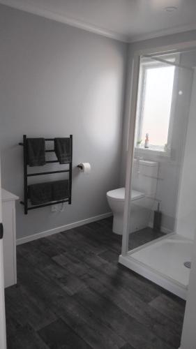 a white bathroom with a toilet and a window at The Quiet Paddock in Kairanga