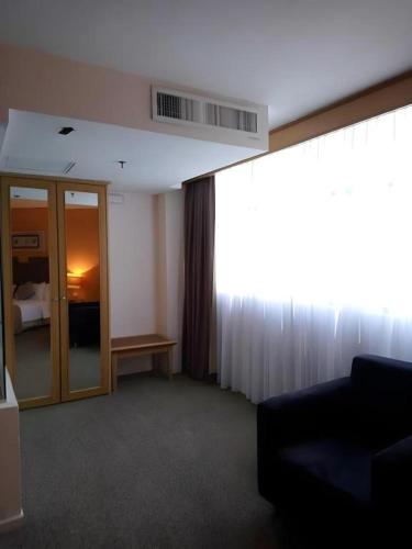 a hotel room with a room with a window and a couch at Grand Barakah Hotel in Kuala Lumpur