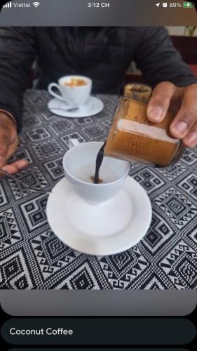 a person pouring coffee into a cup on a table at H'mong Cổ Trấn Sapa Homestay & Restaurant in Sa Pa