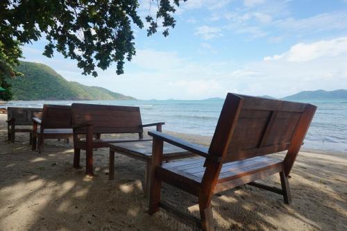 three benches sitting on the beach near the water at The Tropical Beach Resort in Ko Chang