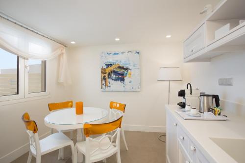 a white kitchen with a white table and chairs at Mareggio Exclusive Residences & Suites in Gythio