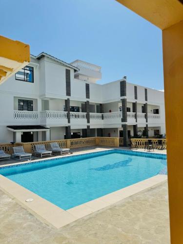 a swimming pool in front of a building at Wendy's Da-Azizi Homes Diani 2 in Diani Beach