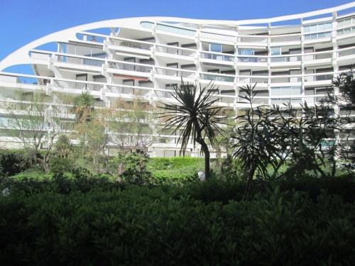 a large white building with a palm tree in front of it at Vittoria Immobilier 2 - Vue Dégagée - Terrasse - chèques vacances acceptés in La Grande Motte