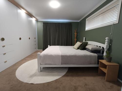 a bedroom with a white bed and green walls at Brightwater Beauty in Brightwater
