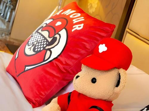 a teddy bear wearing a red hat next to a pillow at Radegast Hotel CBD in Beijing