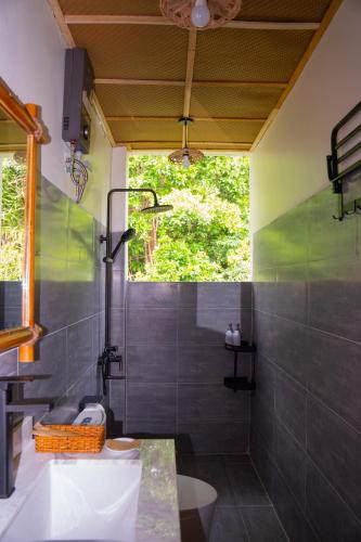 a bathroom with a sink and a shower with a window at Forest Home Phu Quoc is located beside the forest and on a hillside in Phú Quốc