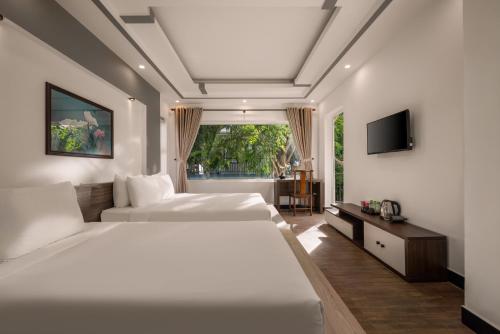 a bedroom with two white beds and a television at Numa Villa Near Old Town Hoi An in Hoi An