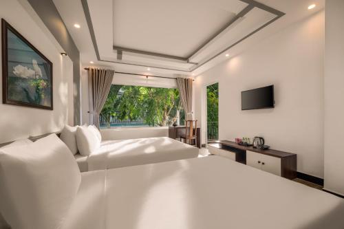 a white bedroom with two beds and a window at Numa Villa Near Old Town Hoi An in Hoi An