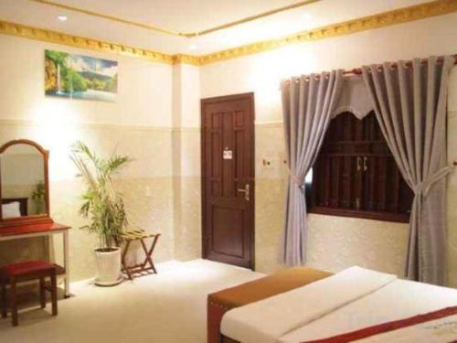 a bedroom with a bed and a table and a window at Au Lac Hotel in Thu Dau Mot