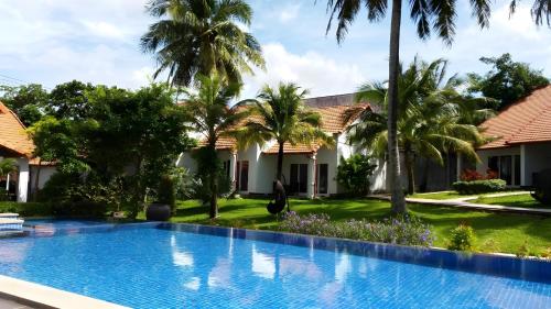 a swimming pool in front of a house with palm trees at Terrace Phú Quốc in Phu Quoc