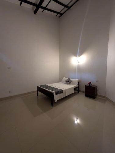 a white room with a bed and a lamp at Kaz N Ray Apartment Negombo in Negombo