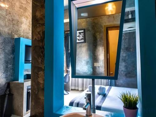 a mirror in a room with a bed and a sink at The B Ranong Trend Hotel in Ranong