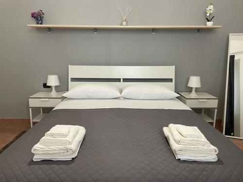a bedroom with a large bed with two white towels on it at Miele Living Home - Comfort in the Heart of Vercelli in Vercelli
