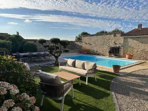 a patio with a couch and a swimming pool at Gîte L'Apothicaire in Montaigu-Vendée