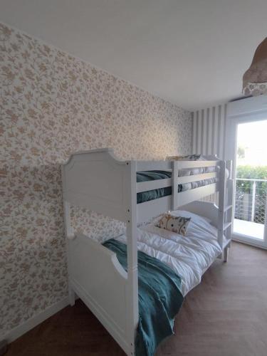 a white bunk bed in a room with a window at Gîte L'Apothicaire in Montaigu-Vendée