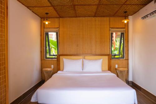 a bed in a room with two windows at Forest Home Phú Quốc in Phu Quoc