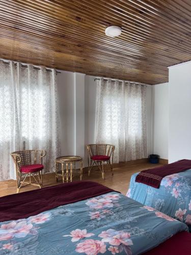 a bedroom with a bed and chairs and windows at Guras Homestay Chimney in Darjeeling