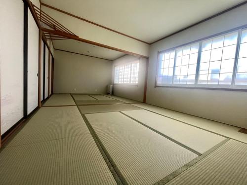 an empty room with a large window and white floors at Snowfox Nozawa in Nozawa Onsen