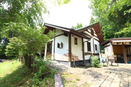a small white house with a porch at 阿蘇山麓のヴィラShijin南阿蘇 in Minami Aso