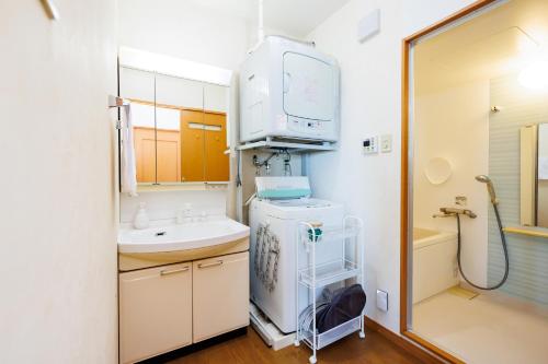 a bathroom with a sink and a washing machine at kafuulivimg nagahama in Yomitan