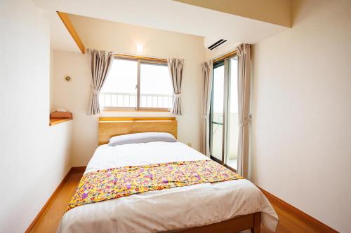 a bed in a room with a window at kafuulivimg nagahama in Yomitan