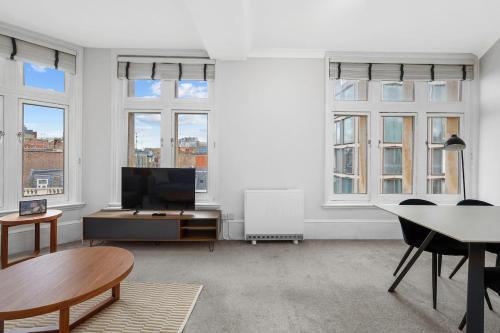 a living room with a tv and a table and some windows at 1 Bedroom Apartment Near Leicester Square in London