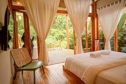 a bedroom with a bed and a chair and a porch at ลมหายใจ โฮมสเตย์ บ่อเกลือ น่าน Lomhaijai Homestay in Ban Pha Khap