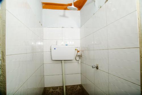 a bathroom with a toilet in a white tiled wall at The Ankh Guest House in Kampala