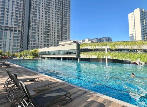 une piscine avec des chaises et un bâtiment avec de grands bâtiments dans l'établissement Brand NEW Modern Cozy Retreats 3BR2B2P for 6, à Batu Kawan