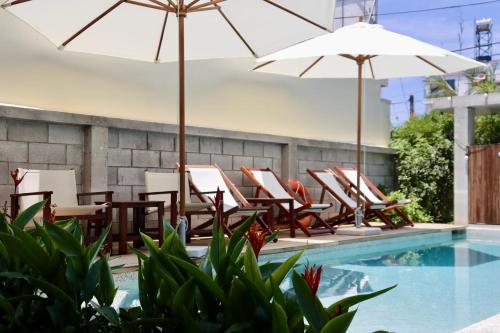 a group of chairs and umbrellas next to a swimming pool at Marvelous Homestay Hoi An in Dien Ban