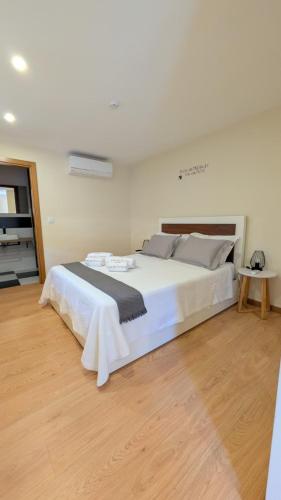 a large white bed in a room with a wooden floor at Casa do Cruzeiro in Alvações do Corgo