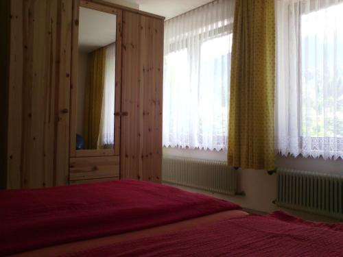 1 dormitorio con cama, espejo y ventanas en Appartements Zankl, en Kötschach-Mauthen