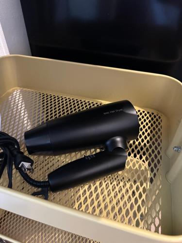 a black hairdryer in a plastic container at Minato House 101 in Fukuoka