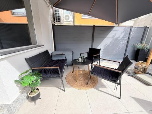 Un patio con dos sillas y una mesa y una sombrilla. en Asitad DeLuxe Apartments, en Ruse