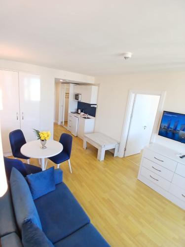 Una sala de estar con un sofá azul y una mesa. en Orbit apartments near the beach, en Angisa