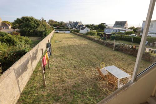 a table and a chair in a yard next to a fence at Studio privatif GR34 & mer au bout du jardin in Lanildut