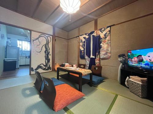 a living room with a table and a tv at Oyado Shogoin in Kyoto