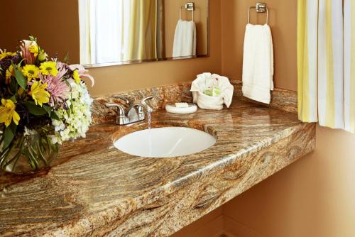 a bathroom counter with a sink and a vase of flowers at The Lodge at Turbat's Creek in Kennebunkport