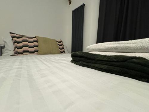 a bed with white sheets and pillows on it at 38LYW Large Ensuite Room - Stratford, London in London