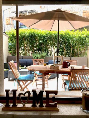 a table with an umbrella and two chairs and a table with a bench at Agréable T2 calme centre-ville d'Annot in Annot
