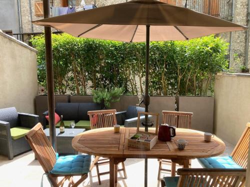 a wooden table and chairs with an umbrella at Agréable T2 calme centre-ville d'Annot in Annot