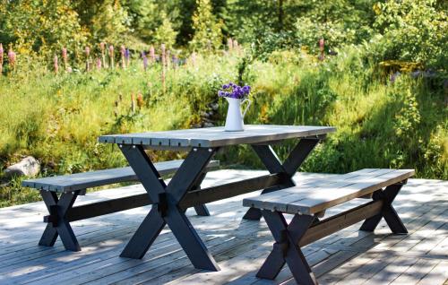 a picnic table and bench with a vase of flowers on it at 3 Bedroom Amazing Home In Vrigstad in Vrigstad