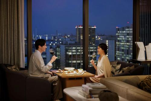 a man and woman sitting in a living room drinking wine at The Westin Yokohama in Yokohama